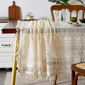 Detail of bohemian lace tablecloth showing beige hollow textures and tassel fringe edge