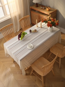 Close-up of bohemian beige lace tablecloth with hollow patterns and tassel fringe details