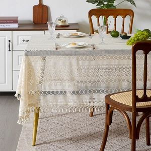 Detail of beige lace tablecloth with tassels showing geometric patterns in a warm dining room