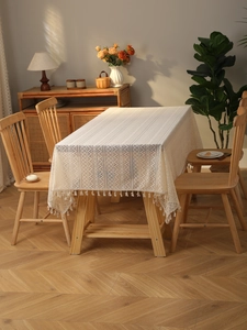 Close-up of bohemian beige lace tablecloth with geometric patterns and white cotton tassels