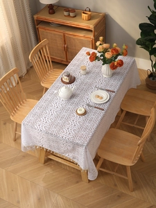 Close-up of white bohemian lace tablecloth with floral hollow embroidery and fringe