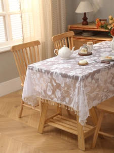Close-up of white bohemian lace tablecloth with floral hollow patterns and tassel fringe