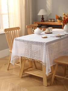 Close-up of white bohemian lace tablecloth featuring fringe edges and woven patterns