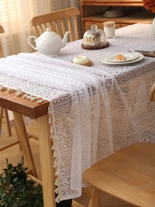 Macro detail of white lace tablecloth with delicate floral embroidery and fringed edges