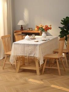 Detail of cream white lace tablecloth with hollow floral patterns and elegant tassels