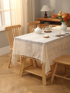 Detail of bohemian lace tablecloth with intricate floral cutouts and tassel fringe edges