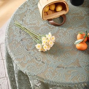 Detail of sage green lace round tablecloth with ruffles and vintage floral patterns