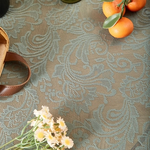 Detailed close-up of light green lace tablecloth with French floral pattern and ruffles