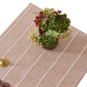 Brown rustic linen table runner with white embroidery and tassels for dining room