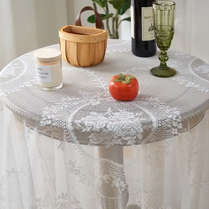 Detail of white round lace tablecloth featuring intricate rose patterns and mesh edges