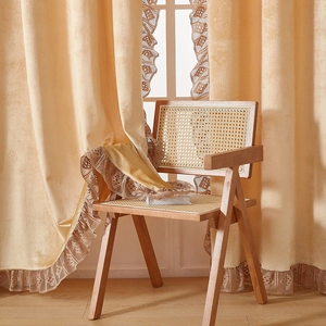 Detail of cream velvet thermal curtain with delicate lace trim and heavy drape texture