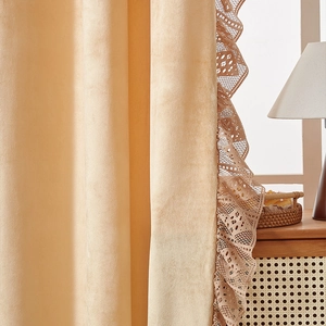 Detail of apricot velvet curtain with elegant lace trim in a cozy home setting