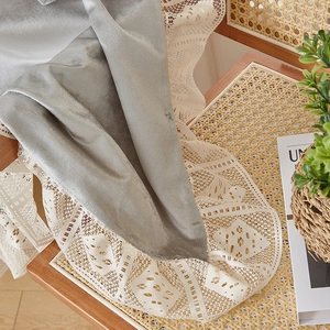 Detailed view of grey velvet runner with intricate cream crochet lace edges on a chair
