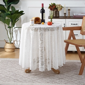 Detailed close-up of white lace tablecloth with vintage floral embroidery and wavy edges