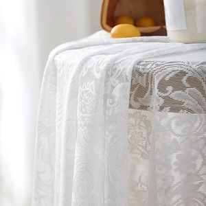 Close-up of white floral lace tablecloth with elegant ruffled edge and mesh texture