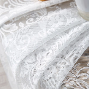 Close-up of white French lace tablecloth showing intricate floral patterns and mesh texture