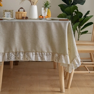Detail of beige linen tablecloth with floral ruffle edges and rustic textures