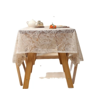 Bohemian white lace tablecloth with floral embroidery and wavy edges on wooden table
