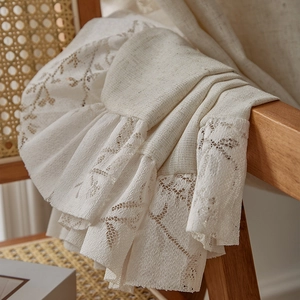 Vintage beige linen curtain with floral ruffle lace draped over a wooden chair