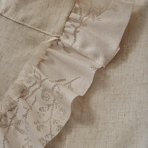 Close-up of vintage linen curtain with delicate floral lace trim and textured fabric