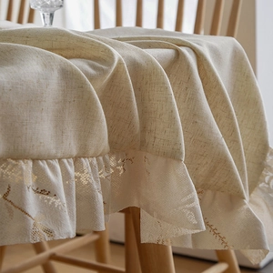 Detail of beige cotton linen tablecloth featuring exquisite floral lace embroidered edges