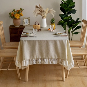 Detail of beige linen tablecloth featuring delicate floral lace and ruffled edges