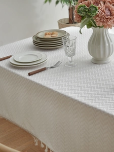 Close-up of herringbone texture and white tassels on a vintage rectangular tablecloth
