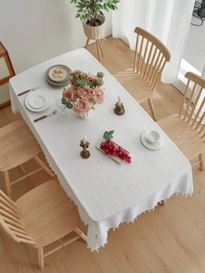 Close-up of white herringbone textured tablecloth with decorative white tassels