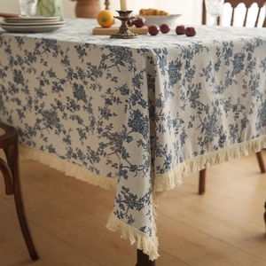 Macro shot of blue floral cotton linen tablecloth with delicate beige tassel edge details
