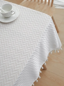 Close-up of beige woven tablecloth featuring herringbone texture and fringe edges