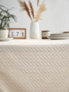 Detail of light beige herringbone textured tablecloth with premium cotton-linen weave
