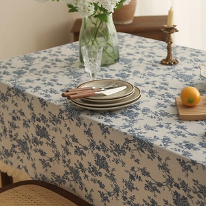 Linen table runner with blue floral pattern and tassels in a rustic home setting
