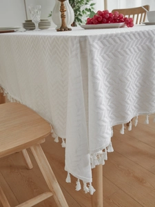 Close-up of white chevron pattern tablecloth with elegant fringe trim on wooden table