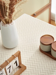 Detail of beige herringbone woven tablecloth texture with minimalist home decor items