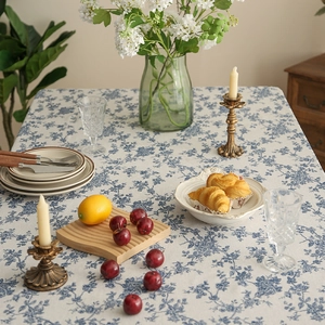 Blue floral linen tablecloth on table with ceramic dishes and a candle holder