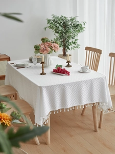 Detail of white rectangular tablecloth with 3D weave texture and elegant tassel edges