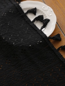 Close-up of black hollow lace tablecloth featuring intricate floral patterns and fringe edges