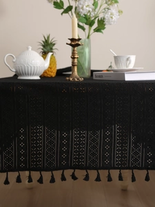 Detail of black hollow lace tablecloth with delicate floral patterns and tassel fringe