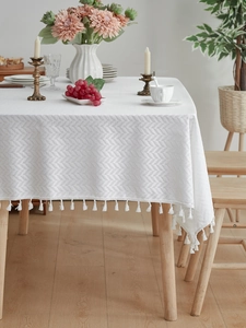 Close-up of white herringbone textured tablecloth with elegant tassel edge detail