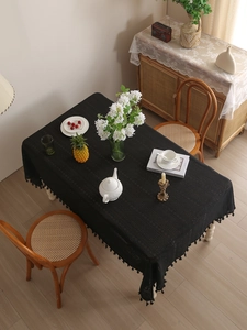 Detail of black hollow lace tablecloth with delicate tassels in a vintage home setting