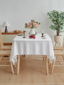 Close-up of white rectangular tablecloth with textured fishtail weave and tassel fringe
