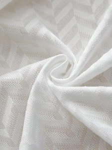 Macro detail of white herringbone weave fabric showing soft texture and premium linen material