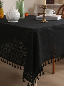 Close-up of black hollow lace tablecloth featuring crochet geometric patterns and tassels