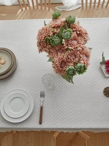 Detailed view of light gray herringbone tablecloth with delicate fringe on a dining table