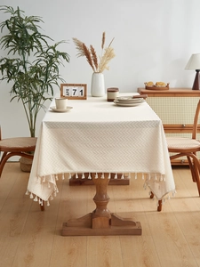 Macro detail of cream linen tablecloth with herringbone weave and beige fringe edges