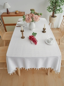 Detail of white rectangular tablecloth with herringbone weave texture and tassel fringe