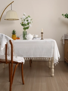 Detail of white hollow lace tablecloth with delicate geometric patterns and fringe edges
