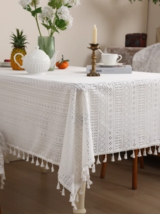 Close-up of white crochet lace tablecloth with hollow patterns and fringe tassels