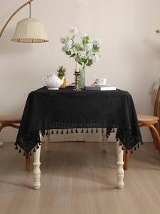 Close-up of black hollow lace tablecloth with elegant tassels in a retro bohemian style