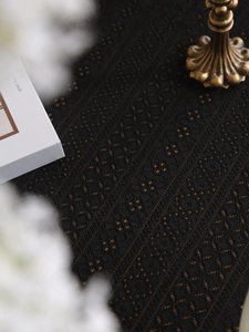 Close-up of black lace tablecloth featuring intricate geometric hollow-out patterns